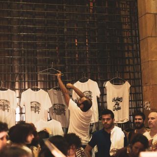 Men in market with T-shirts that have Arabic slogans written on them, by graphic designer Farah Fayyad