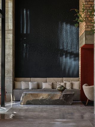 lobby with black and stone walls and large stone slag coffee table, chairs and pillows behind table