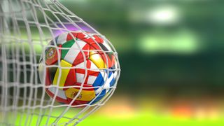 ootball ball with flags of european countries in the net of goal of football stadium - stock photo