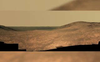 Rusty red landscape showing a large valley and hazy yellow sky.