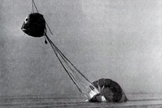 black and white photo of a space capsule landing in water