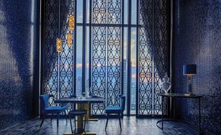 Dining area featuring marble-topped tables, navy blue chairs, and navy tiles on the floor and walls