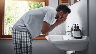 man washing his face at the bathroom sink