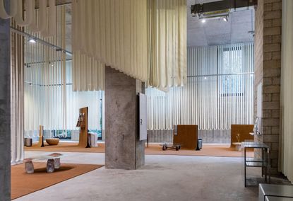 Installation view at the House of Today. The table designs are showcased set on orange carpets.