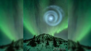 A large swirl of blue light shines above the peak of a hill.