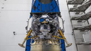 a space lander with protruding legs sits attached to its payload adapter in a white room. The Peregrine lunar lander, built by the Pittsburgh-based company Astrobotic, will launch toward the moon atop a United Launch Alliance Vulcan Centaur rocket on Jan. 8.