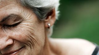 close up on the crossfeet on an older woman's face as she smiles with her eyes closed