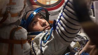 an astronaut in a spacesuit inside a cramped spacecraft