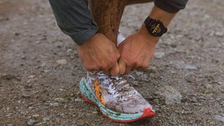 Garmin Forerunner 255 on wrist while man ties shoes