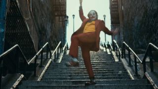 Joaquin Phoenix as The Joker dancing on a long staircase.