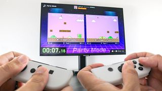 Two people playing Nintendo World Championships: NES Edition with a Joy-Con turned sideways on a monitor