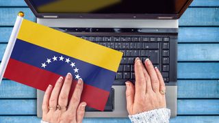 Woman hands and flag of Venezuela on computer, laptop keyboard