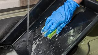 Hand washing a baking sheet in the sink