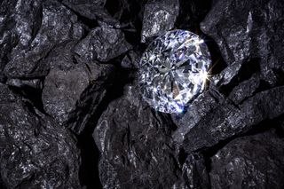 A sparkling diamond amongst dark coal-like rock.