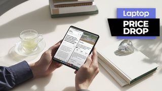 Man holding Galaxy Z fold 4 over a table next to books and a glass cup and saucer