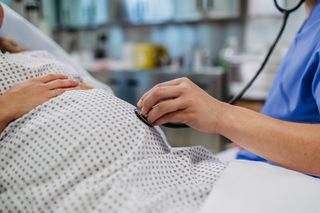 Doctor using stethoscope to listing baby’s heartbeat