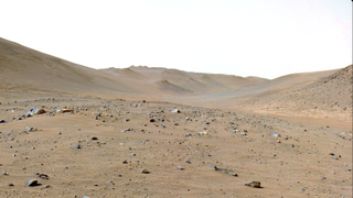 a rocky, rust colored barren, hilly landscape littered with various rocks and brown dust.