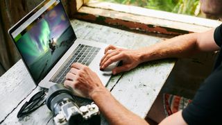 Man using one of the best photo editing apps for astrophotography on a laptop to edit astrophotographs