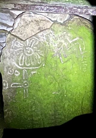 ancient geometric shapes on an old rock in the sunlight. some of the shapes are thought to represent the sun