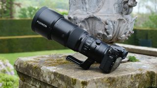 Fujifilm GFX 100S II camera and GF 500mm lens sitting on a a stone wall