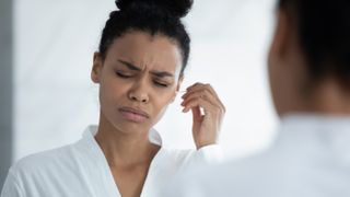 Woman cleaning her ear with a cotton swab.