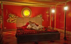 Still from 'Orlando, My Political Biography' by Paul Preciado: actor lying on bed in red room