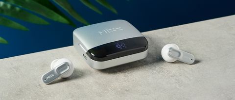 a closed case of mixx streambuds ultra mini rests on a table with two earbuds half in the shot