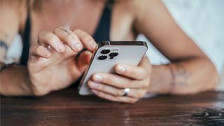 A person holding an iPhone in one hand and touching the screen with the other hand