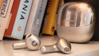 The Xiaomi Buds 5 on a bookshelf.