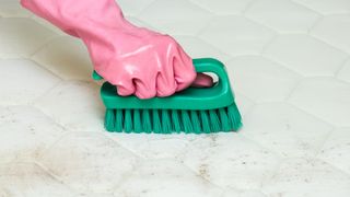 Using a brush to clean a mattress topper