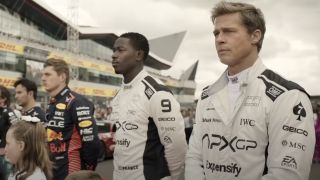 Sonny Hayes (Brad Pitt) and Joshua Pearce stand on a track with others in F1
