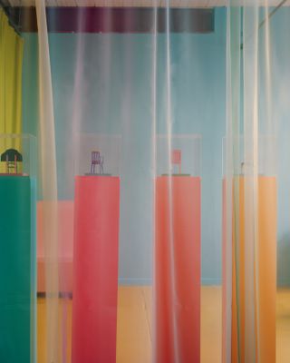 Model chairs on plinths behind sheer curtain in Yinka Ilori studio, London