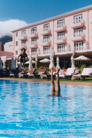 woman's legs in air as she does handstand in hotel pool