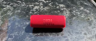 A red JBL Flip 6 on a weathered table outside.