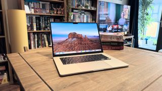 The 2024 MacBook Air M3 on a wooden table in front of a bookshelf.