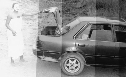 Lady with a face mask on opening the boot of a car