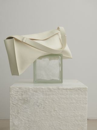 White leather bag on balancing on glass box and cube