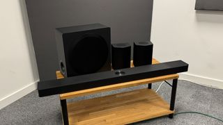 LG S95TR soundbar package on wooden AV rack in corner of room