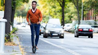 Man in smart attire riding an Electric scooter on the road