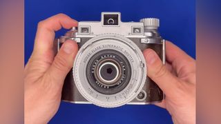 A Kodak Medalist II being handled on a blue background 