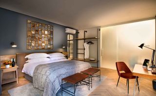 Bedroom with white linen and a gray throw. There is a study unit and two bedside tables and a wooden floor.