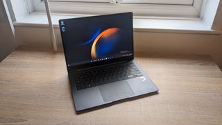 The Samsung Galaxy Book3 Pro 14-inch laptop pictured atop a wooden desk.