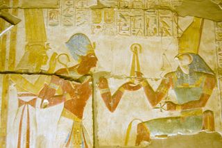 Ancient Egyptian god Horus with Seti and Isis and golden fly-whisk. Interior wall of the Temple of Osiris at Abydos, Egypt.