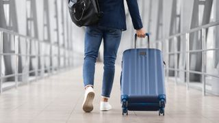 Someone pulling a suitcase through an airport