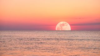 A vibrant moonlight the ocean, with a fiery sky and calm waters