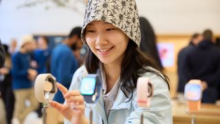 A woman wearing a hat standing in front of an Apple Watch display