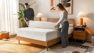 Image shows a man and a woman unrolling the world's best mattress topper, the Tempur-Adapt Mattress Topper, onto their bed