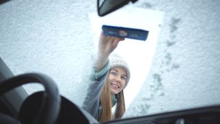 Woman defrosting car windshield