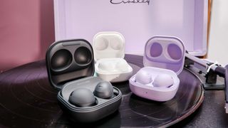 Galaxy Buds Pro 2 in purple, white and black showing charging case open and placed on vinyl record