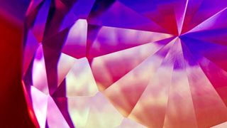 Macro photo of a faceted crystal with purple and pink light effects.